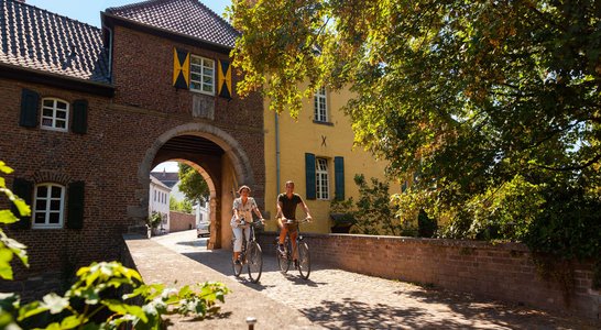 Radfahrer unter dem Eulentor auf Schloss Bedburg